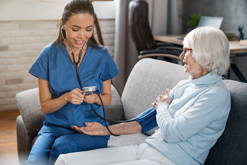 female nurse checking blood pressure of senior woman
